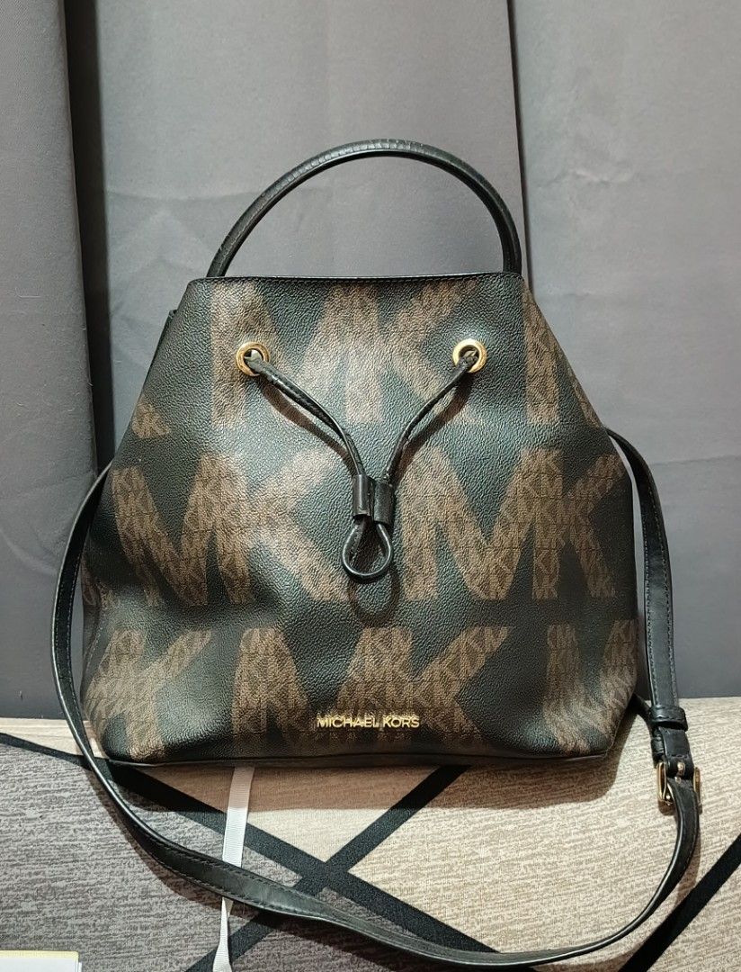 AUTHENTIC Michael Kors Bucket Bag (Category: Luxury Bags & Wallets) located in Quezon City. Submitted by kazuxxxx (Listing ID 1470170055, Image 2). Description: - Brand: Michael Kors - Color: Dark Brown with signature MK monogram and black leather trim - Hardware: Gold-tone - Closure: Drawstring top - Straps: Short top handle and adjustable long strap for crossbody wear - Details: Small gold Michael Kors lettering on the front.