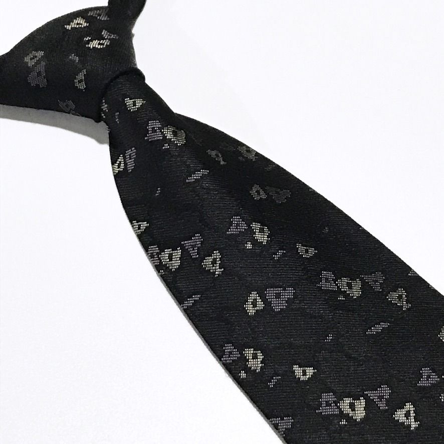 AXUM Vintage Abstract Black Neck Tie (Category: Ties) located in Taguig. Submitted by retrogaze (Listing ID 1470210817, Image 1). Description: This vintage 100% silk necktie by AXUM Men features a solid black ground woven with a subtle, slubbed texture that lends refined tactile depth to the fabric. The body is decorated with an understated abstract geometric pattern of scattered, pixelated micro-shapes woven in soft cream, taupe, and muted slate