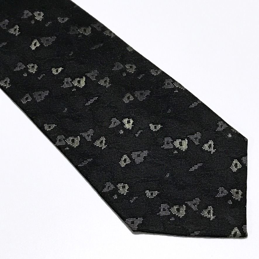 AXUM Vintage Abstract Black Neck Tie (Category: Ties) located in Taguig. Submitted by retrogaze (Listing ID 1470210817, Image 2). Description: This vintage 100% silk necktie by AXUM Men features a solid black ground woven with a subtle, slubbed texture that lends refined tactile depth to the fabric. The body is decorated with an understated abstract geometric pattern of scattered, pixelated micro-shapes woven in soft cream, taupe, and muted slate