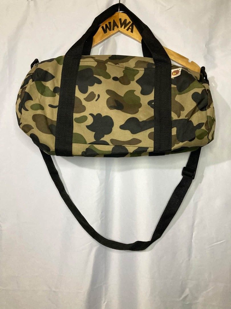 BAPE DUFFLE BAG (Category: Sling Bags) located in Naga. Submitted by wwy3ips (Listing ID 1470249623, Image 2). Description: A BATHING APE 2013 SUMMER COLLECTION BAPE CAMO DUFFLE BAG BRAND:A BATHING APE (BAPE) COLLECTION:2013 SUMMER COLLECTION TYPE: DUFFLE / DRUM BAG COLOR:GREEN, BROWN, AND BLACK CAMOUFLAGE MATERIAL:POLYESTER DIMENSIONS: APPROX. 42 CM × 20 CM × 20 CM FEATURES:DUAL CARRY HANDLES, ADJUSTABLE SHOULDER STRAP, ZIPPER CLOSURE, AND SPACI