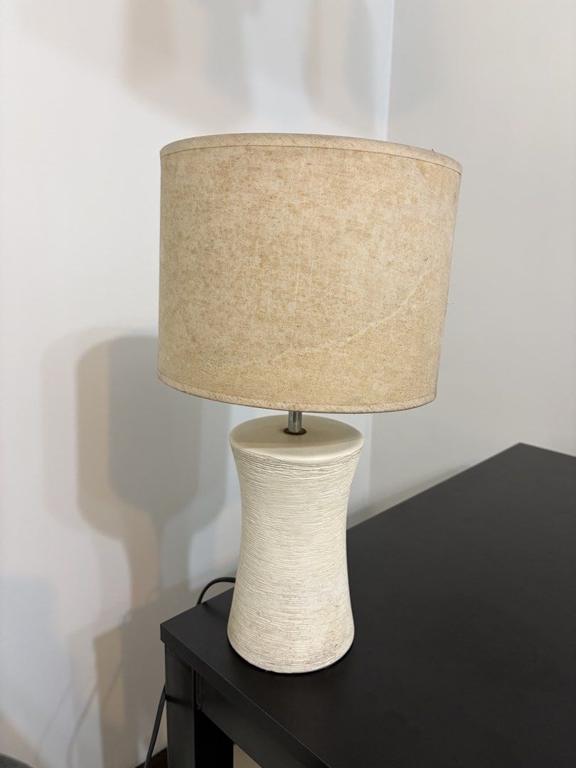 Bedside table lamp with textured ceramic base and fabric shade (Category: Lighting) located in Makati City. Submitted by thomasgo10 (Listing ID 1470149209, Image 2). Description: - Textured white ceramic base with a stylish ribbed finish - Fabric drum shade that creates a cozy, warm glow - Standard bulb socket, ideal for bedside tables and desks Price 1200 Dimensions: 43Hx24W cm Location: Greenfield Mandaluyong - Compact and space-saving design f
