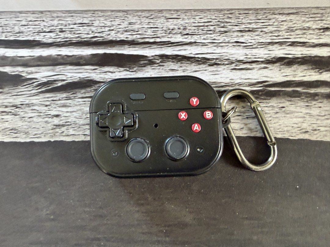 Black Gaming Controller Earphone Case with Keychain (Category: Cases & Sleeves) located in Makati City. Submitted by dennis_dumlao (Listing ID 1470247641, Image 1). Description: - Design: Retro video game controller shape in sleek black silicone with detailed red and grey buttons - Protection: Durable silicone material shields your earphones from drops and scratches - Portability: Includes a sturdy metal carabiner to easily clip onto bags, belt l