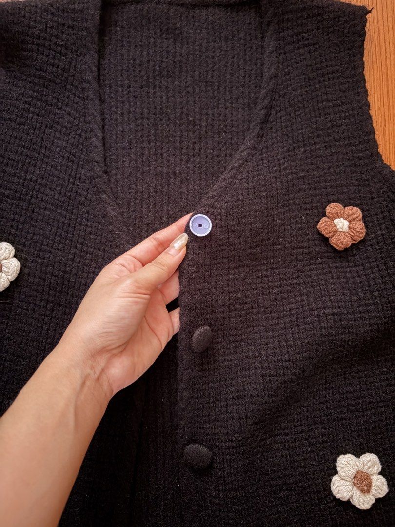 Black knit floral button vest (Category: Sleeveless) located in San Pedro. Submitted by iarruh (Listing ID 1470196305, Image 2). Description: - Style: Black knit vest with charming white and brown crochet flower details - Neckline & Closure: V-neck with front button closure (includes one light-colored replacement button near the top) - Fit & Fabric: Comfortable, soft fabric, perfect for layering over plain tees or shirts - The outer part of the f