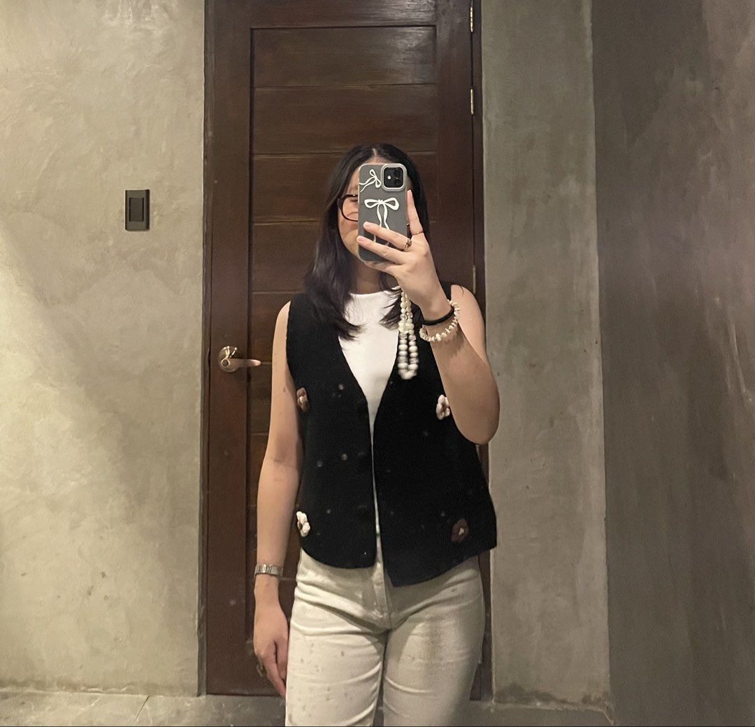 Black knit floral button vest (Category: Sleeveless) located in San Pedro. Submitted by iarruh (Listing ID 1470196305, Image 3). Description: - Style: Black knit vest with charming white and brown crochet flower details - Neckline & Closure: V-neck with front button closure (includes one light-colored replacement button near the top) - Fit & Fabric: Comfortable, soft fabric, perfect for layering over plain tees or shirts - The outer part of the f