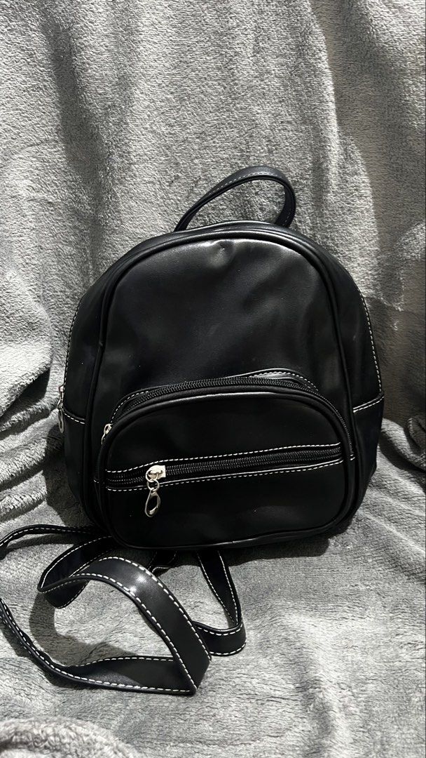 Black leather mini backpack (Category: Backpacks) located in Manila. Submitted by asdfghjkl.mountain (Listing ID 1470278269, Image 1). Description: - Color & Material: Black faux leather - Design: White contrast stitching along seams and straps - Storage: Front zipped pocket with round silver puller - Carry Options: Adjustable shoulder straps and top carry handle - Size: Small everyday mini backpack.