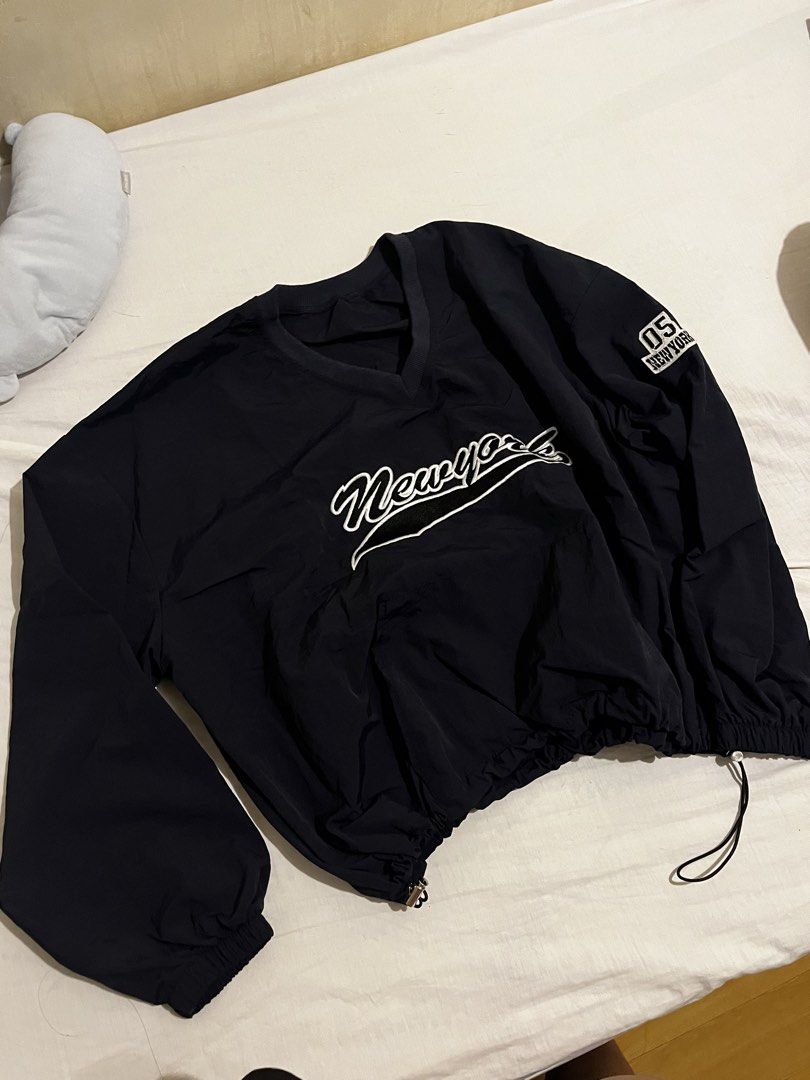 Black New York 05 Athletic Windbreaker Pullover (Category: Coats, Jackets and Outerwear) located in San Fernando. Submitted by angelhave_wings (Listing ID 1470291399, Image 1). Description: - Color: Black - Style: Lightweight pullover windbreaker with V-neck collar - Branding: White 'Newyork' script embroidery on chest and '05 New York' patch on left sleeve - Fit & Comfort: Elastic cuffs and adjustable drawstring hem for a customizable fit - Vers