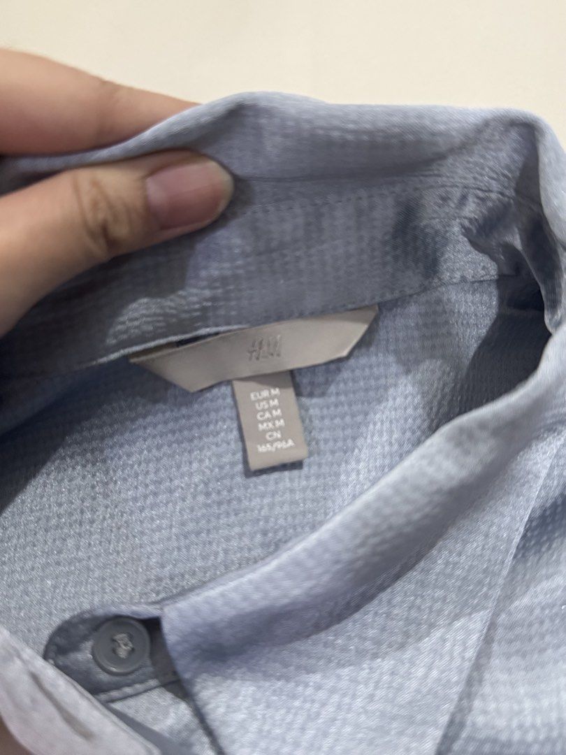 Blue-Gray Textured Button-Down Shirt (Category: Blouses) located in Manila. Submitted by buymiclothes.47 (Listing ID 1470336450, Image 3). Description: H&M Blue-Gray Textured Button-Down Shirt | M Preloved H&M long-sleeve button-down shirt in a pretty light blue-gray shade with a subtle sheen 🩵 * Size M * Slightly shiny, textured fabric * Classic collar and button-front closure * Long sleeves with button cuffs * Relaxed fit with curved hem * App