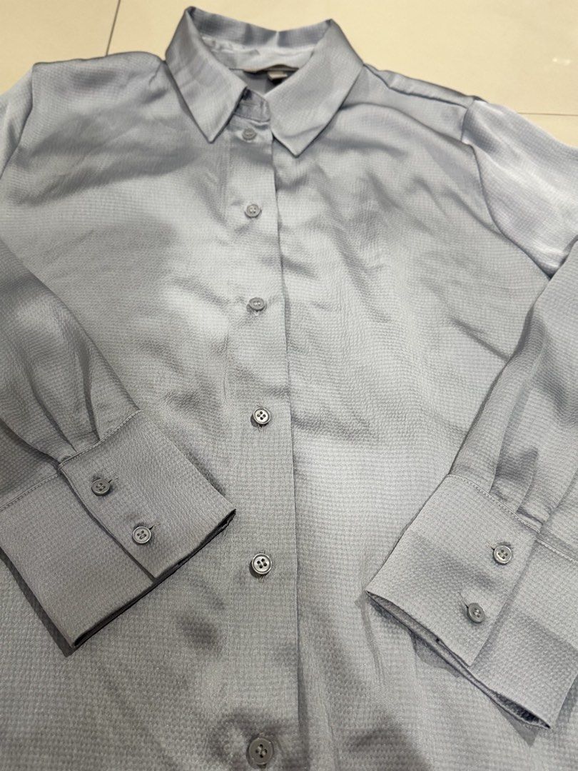 Blue-Gray Textured Button-Down Shirt (Category: Blouses) located in Manila. Submitted by buymiclothes.47 (Listing ID 1470336450, Image 2). Description: H&M Blue-Gray Textured Button-Down Shirt | M Preloved H&M long-sleeve button-down shirt in a pretty light blue-gray shade with a subtle sheen 🩵 * Size M * Slightly shiny, textured fabric * Classic collar and button-front closure * Long sleeves with button cuffs * Relaxed fit with curved hem * App