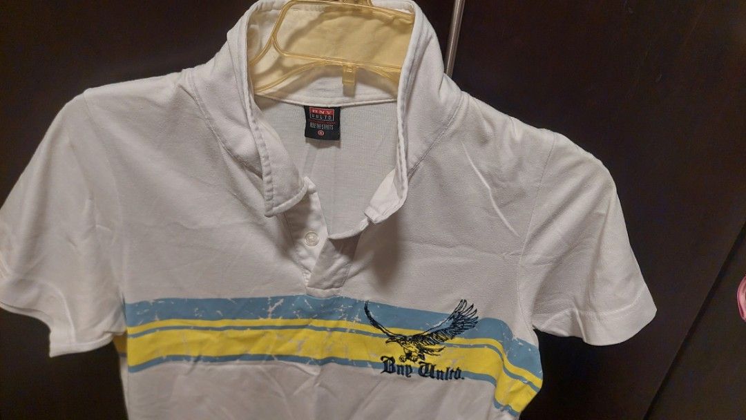 Bny Unltd White Polo Shirt with Graphic Eagle Print (Category: Tshirts & Polo Shirts ) located in Paranaque City. Submitted by daddyu (Listing ID 1470179111, Image 1). Description: - Brand: BNY Unltd. - Color: White with bold blue and yellow chest stripes - Design: Flying eagle graphic with BNY Unltd. lettering - Details: Short sleeves, classic collar, front button-down closure - Condition/Fit: Casual everyday wear, size tag visible on inner coll