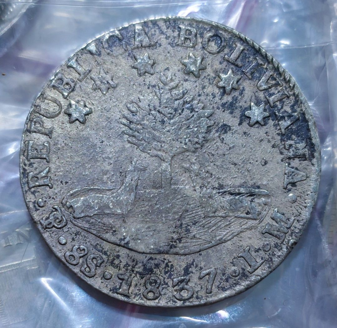 Bolivia 8 Soles Silver Coin 1837 (Category: Currency) located in Taguig. Submitted by ezekiel103 (Listing ID 1470221897, Image 1). Description: - Authentic 1837 Bolivia silver coin - Obverse features Republica Bolivia text, tree, and alpacas - Reverse features Bolivar portrait and Libre Por La Constitucion text - Visible mint marks near the bottom edge - Features heavy natural toning, surface wear, and dark patches from circulation - Details rema