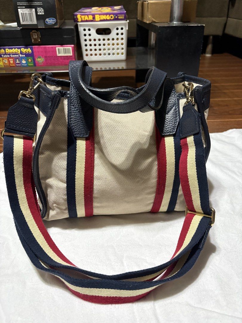 bonfanti made in italy bag (Category: Tote Bags) located in Bulacan. Submitted by love2loved (Listing ID 1470283729, Image 2). Description: - Material: Beige canvas body with dark navy leather trim - Design: Iconic red, cream, and navy striped webbing on front and back - Hardware: Gold-tone hardware with protective metal feet on a structured base - Interior: Clean interior with patterned lining - Versatility: Includes dual top handles and a match