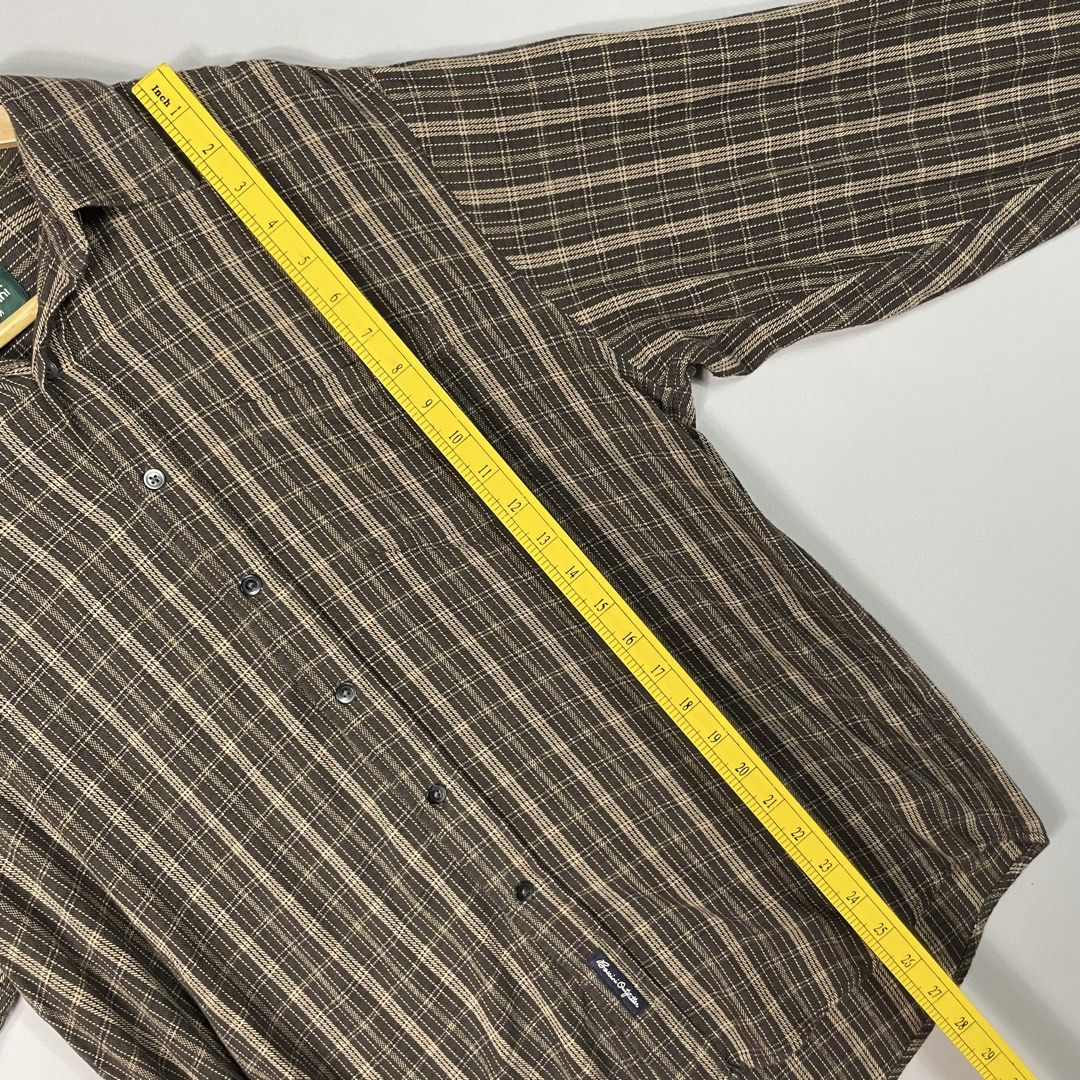 Bossini | Dark Brown Patterned Plaid Checkered Flannel (Category: Tshirts & Polo Shirts ) located in Norzagaray. Submitted by sevenjscloset (Listing ID 1470254062, Image 3). Description: - Brand: Bossini - Style: Dark brown plaid flannel shirt - Size: Medium (Length: 27", Width: 20") - Fit reference: Model is 5'10" and 70kg - Features: Classic checkered pattern, front button closure, chest pocket - Condition: Great vintage piece, no flaws.