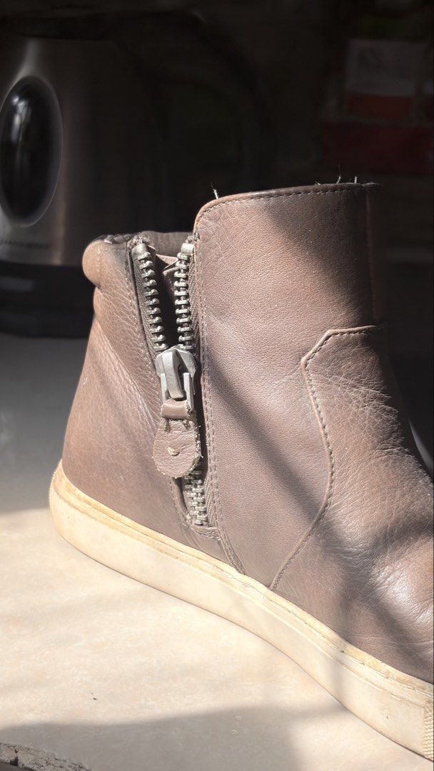 Brown leather ankle boots with side zippers (Category: Boots) located in Manila. Submitted by vexie.nyahmmy (Listing ID 1470209367, Image 3). Description: - Material: Brown leather with natural creasing on the toe box from wear - Sole: Comfortable sneaker-style rubber sole with minor scuff marks - Closure: Double side zippers equipped with convenient leather pull tabs - Design: Ankle height featuring a supportive padded collar - Usage: Versatile 