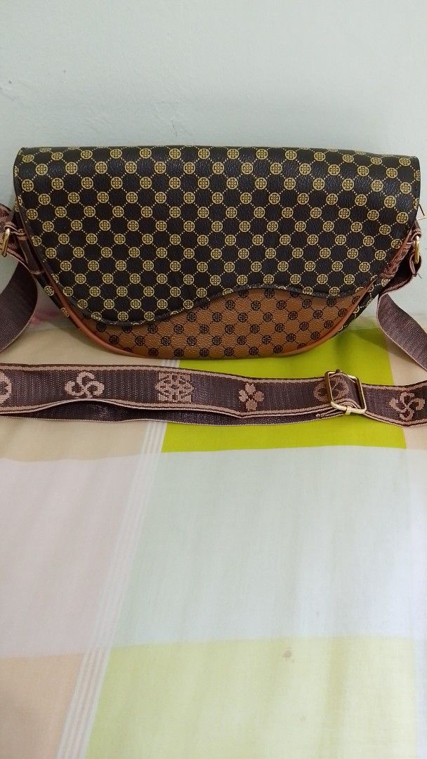 Brown pattern flap crossbody bag with adjustable strap (Category: Cross-body Bags) located in Manila. Submitted by swift.wisemom (Listing ID 1470213387, Image 1). Description: - Color: Brown and dark brown with a stylish geometric pattern - Closure: Flap-over design with secure zip closure underneath - Strap: Adjustable brown fabric strap with clover motifs and gold-tone slider buckle - Interior: Roomy compartment for all your daily essentials - 
