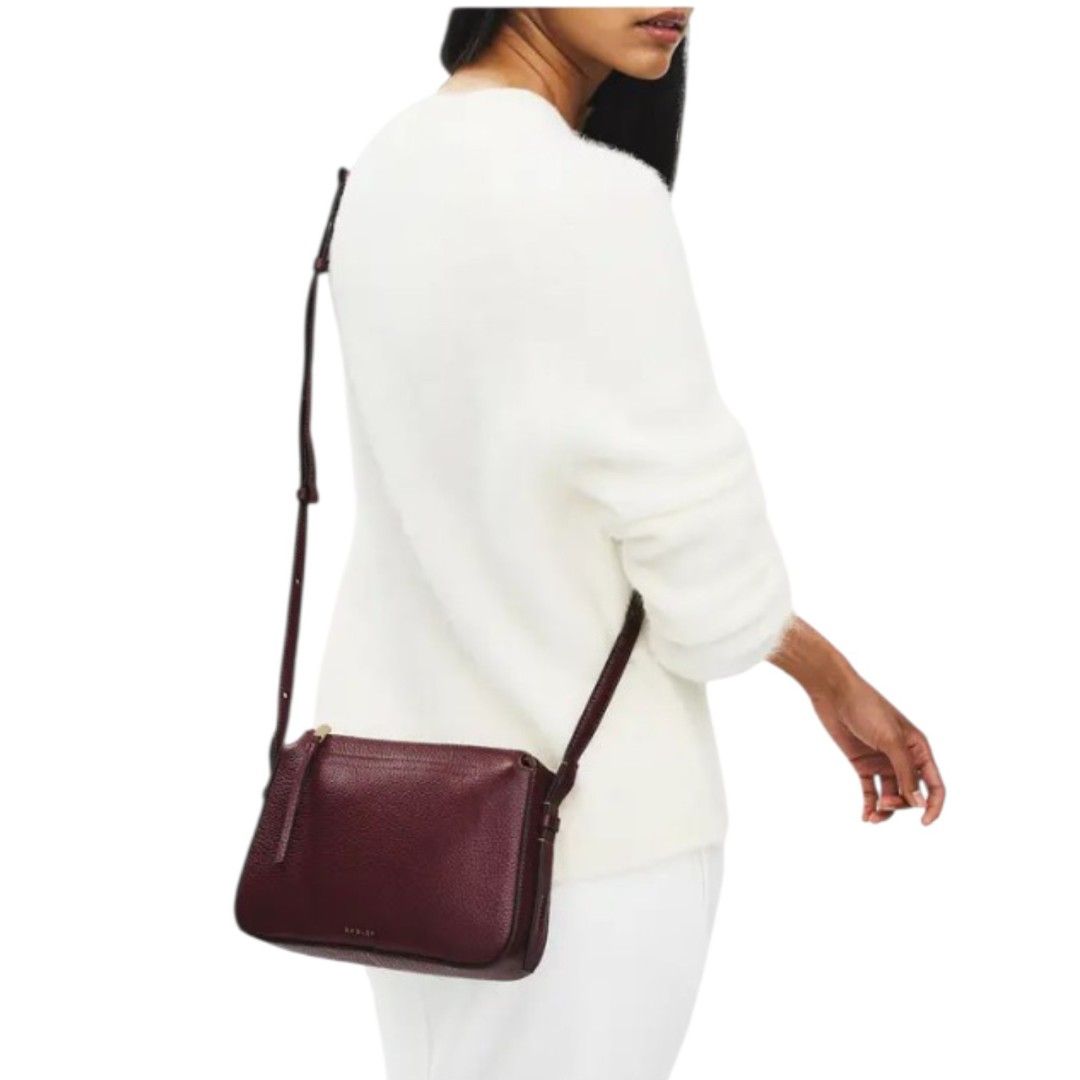 Burgundy Leather Crossbody Bag (Category: Cross-body Bags) located in Mangaldan. Submitted by closetqwin (Listing ID 1470216503, Image 1). Description: - First photo inspo only - Material: Premium dark burgundy pebbled leather with gold-tone hardware - Design: Clean silhouette with a structured base and subtle branding - Closure: Secure top zip closure - Storage: Exterior zippered back pocket with leather pull tabs - Strap: Adjustable strap for c
