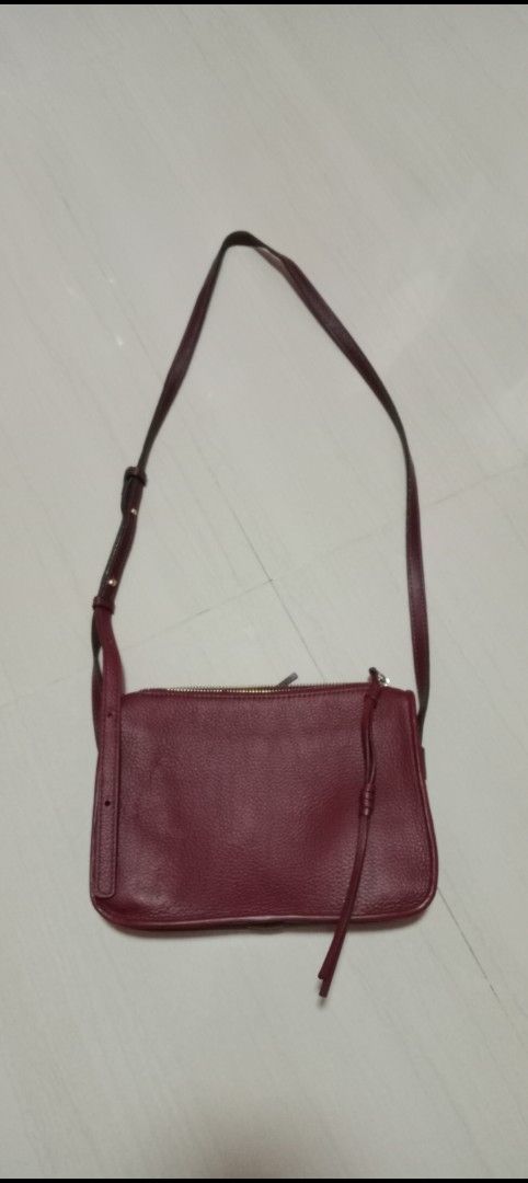 Burgundy Leather Crossbody Bag (Category: Cross-body Bags) located in Mangaldan. Submitted by closetqwin (Listing ID 1470216503, Image 3). Description: - First photo inspo only - Material: Premium dark burgundy pebbled leather with gold-tone hardware - Design: Clean silhouette with a structured base and subtle branding - Closure: Secure top zip closure - Storage: Exterior zippered back pocket with leather pull tabs - Strap: Adjustable strap for c