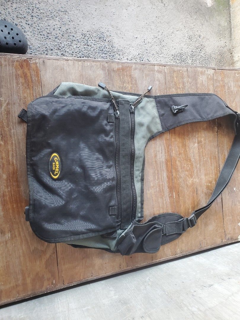 Camel Bag Black Multi-Pocket Messenger Sling Bag (Category: Sling Bags) located in Cavite. Submitted by kyzqway (Listing ID 1470208727, Image 1). Description: Black and green crossbody bag from Camel Bags. Built with tons of storage compartments, including dual front zippered pockets, extra pouches under the main flap, and a small utility pouch on the shoulder strap. Headphone cord pass-through rubber eyelet near the top strap. Heavy-duty black h