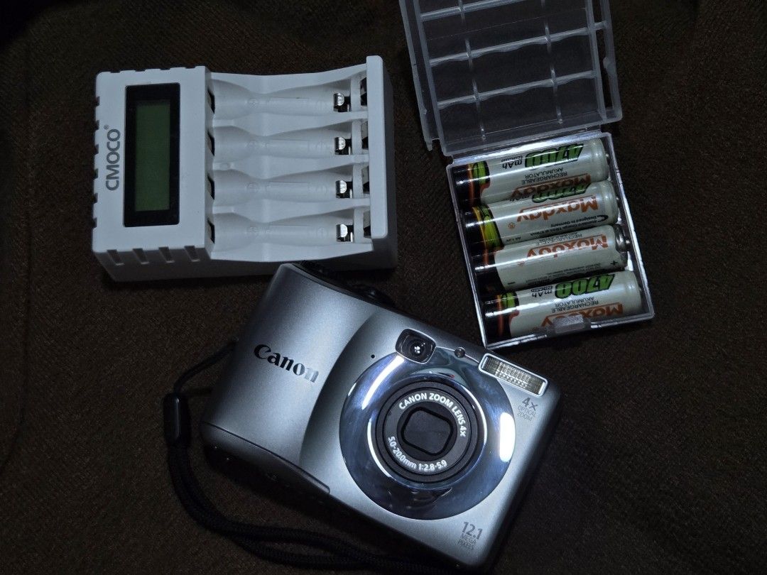 Canon PowerShot Digital Camera Bundle with Charger and Batteries (Category: Cameras) located in Quezon City. Submitted by mikaykie (Listing ID 1470305958, Image 2). Description: Canon PowerShot A1200 12.1 mega pixel Silver body Flash working Zoom working Includes battery charger and a case of four rechargeable batteries Tested and powers on Screen displays fine with screen burn SDHC Card, SD card with Adapter Wrist strap attached RFS: I realized 
