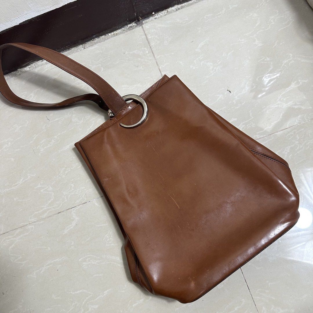 Cartier 1990 Vintage Brown Leather Backpack (Category: Backpacks) located in Manila. Submitted by direcmampu37948 (Listing ID 1470244336, Image 1). Description: - Brand/Era: Authentic vintage Cartier leather backpack from 1990 - Color & Hardware: Rich brown shade paired with silver-tone hardware - Design: Signature ring detail at the top with a versatile, multi-way adjustable strap configuration - Condition Notes: Noticeable surface scratches, sc