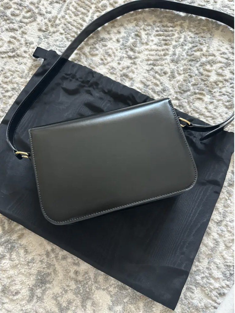 Celine Black Triomphe Crossbody Bag (Category: Luxury Bags & Wallets) located in Abulug. Submitted by jamiecammie (Listing ID 1470272383, Image 2). Description: - Brand: Celine - Material: Premium black calfskin leather - Hardware: Gold-tone Triomphe closure - Strap: Adjustable shoulder strap with buckle detail - Design: Structured shape with a clean front flap - Condition: Like New - Inclusions: Original black Celine dust bag included .