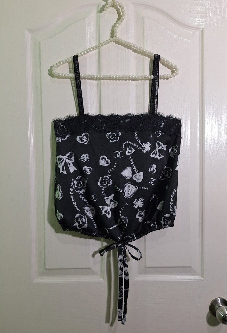 Chanel silk camisole top with prints size 38 small - medium (Category: Luxury Apparel) located in San Pablo. Submitted by allyourbrandedneeds (Listing ID 1470145062, Image 3). Description: - Brand: Chanel - Material: 100% Silk main fabric, cotton & polyamide braid - Design: Black and white heart, clover, and bow print - Details: Black lace trim at neckline, straps with branded Chanel lettering and floral accents - Fit: Adjustable tie hem at the b