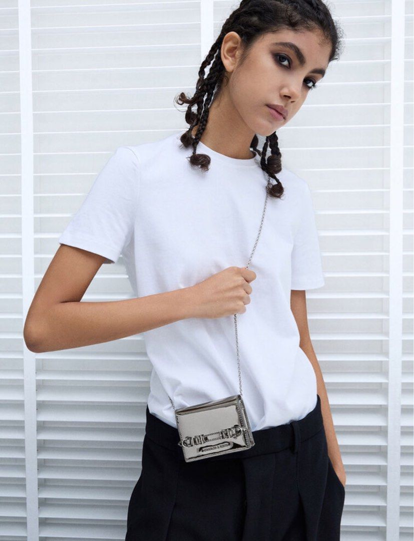 Charles & Keith Metallic Silver Crossbody Bag Wallet (Category: Wallets & Card holders) located in Manila. Submitted by manilynpitero (Listing ID 1470143755, Image 1). Description: - Brand: Charles & Keith - Color: Metallic silver with silver-tone hardware - Design: Double buckle strap detail on the front - Strap: Includes a chain strap for shoulder or crossbody wear - Interior: Features card slots, a zippered coin compartment, and structured poc