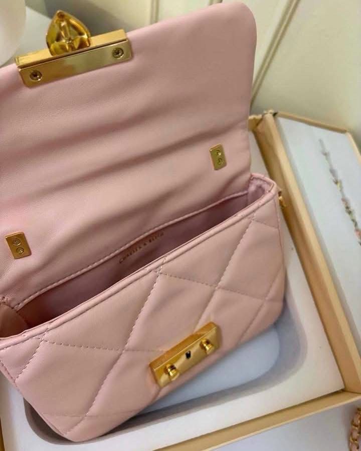 Charles & Keith Quilted Pink Handle Bag Gift Set (Category: Cross-body Bags) located in Manila. Submitted by manilynpitero (Listing ID 1470143470, Image 3). Description: - Brand: Charles & Keith - Style: Pink quilted shoulder bag with gold hardware, top handle, chain strap, and heart clasp closure - Inclusions: Matching butterfly and flower charms, plus an earrings and bracelet set - Packaging: Comes in an original presentation box with ribbon .