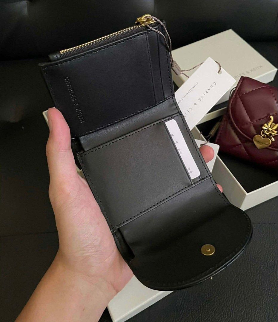 Charles & Keith Quilted Short Wallet with Charm (Category: Wallets & Card holders) located in Manila. Submitted by manilynpitero (Listing ID 1470143993, Image 3). Description: - Brand: Charles & Keith - Style: Quilted short wallet with snap button closure - Details: Adorable gold-tone bow and heart charm on the front flap - Compartments: Multiple card slots, cash compartment, and zippered coin pocket - Inclusions: Comes with box and tags - Colors