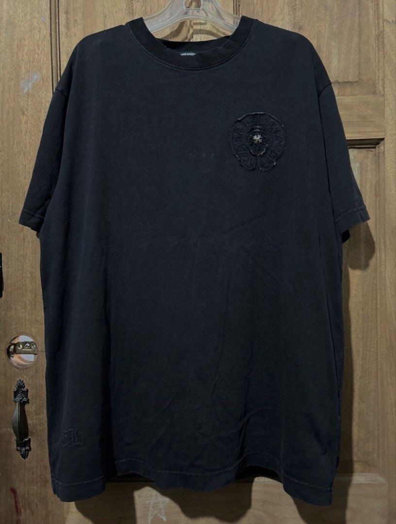 Chrome Hearts Black T-Shirt with Cross Patch Logo (Category: Tshirts & Polo Shirts ) located in Iba. Submitted by gotmethrift (Listing ID 1470295393, Image 1). Description: - Classic heavy cotton wash for a vintage feel - Front chest features the iconic round horseshoe logo patch - Statement large cross patch design on the back - Detailed with signature silver metal dagger hardware - Premium streetwear piece ideal for casual wear or layering - Co