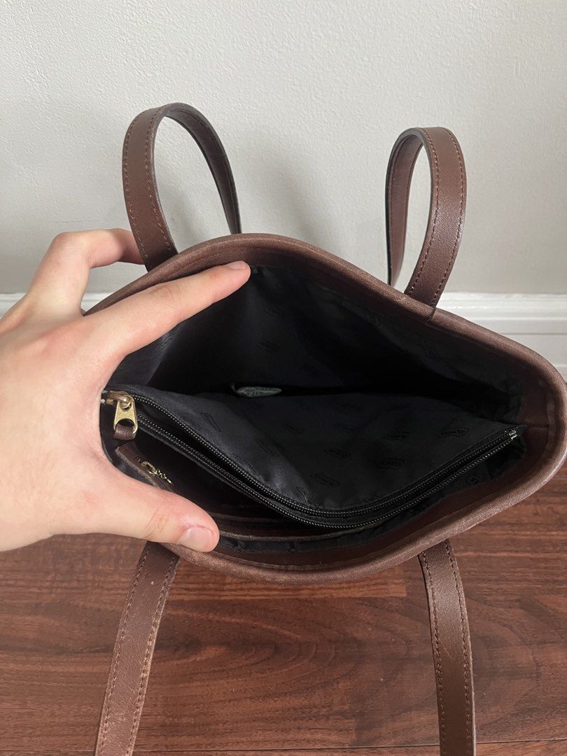 Coach Brown Leather Tote Bag (Category: Luxury Bags & Wallets) located in Quezon City. Submitted by jansen.ng (Listing ID 1470172173, Image 3). Description: - Authentic Coach brown leather tote bag - Dual shoulder straps with matching hangtag included - Fabric-lined interior with zippered compartment and slip pockets - Structured upright style with vertical seam detailing - Condition: Regular signs of handling along edges and handles.
