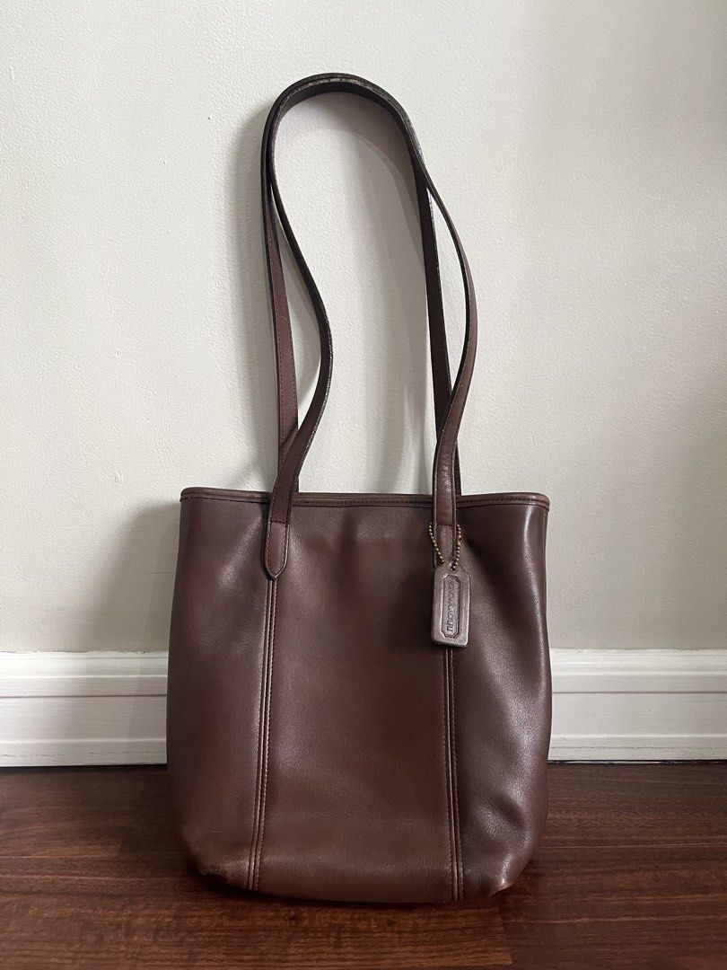 Coach Brown Leather Tote Bag (Category: Luxury Bags & Wallets) located in Quezon City. Submitted by jansen.ng (Listing ID 1470172173, Image 1). Description: - Authentic Coach brown leather tote bag - Dual shoulder straps with matching hangtag included - Fabric-lined interior with zippered compartment and slip pockets - Structured upright style with vertical seam detailing - Condition: Regular signs of handling along edges and handles.