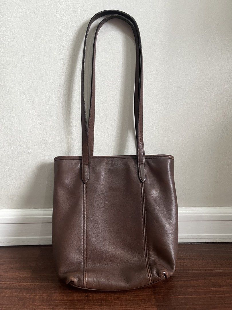 Coach Brown Leather Tote Bag (Category: Luxury Bags & Wallets) located in Quezon City. Submitted by jansen.ng (Listing ID 1470172173, Image 2). Description: - Authentic Coach brown leather tote bag - Dual shoulder straps with matching hangtag included - Fabric-lined interior with zippered compartment and slip pockets - Structured upright style with vertical seam detailing - Condition: Regular signs of handling along edges and handles.