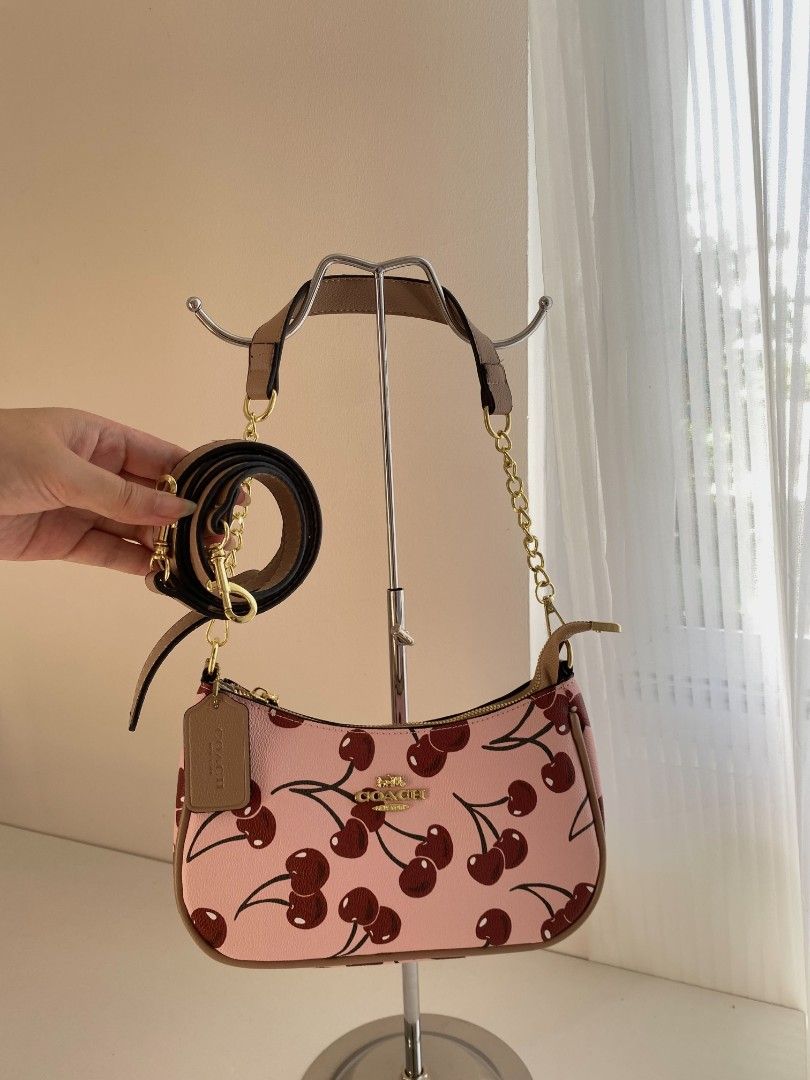Coach Cherry Print Shoulder Bag (Category: Shoulder Bags) located in Manila. Submitted by _louisse (Listing ID 1470170762, Image 1). Description: - Brand: Coach - Material: Pink leather with all-over red cherry print - Hardware: Gold-tone hardware with front Coach logo - Closure: Secure zipper closure - Inclusions: Detachable shoulder strap and matching leather hangtag - Condition: Clean interior and exterior, well-kept.