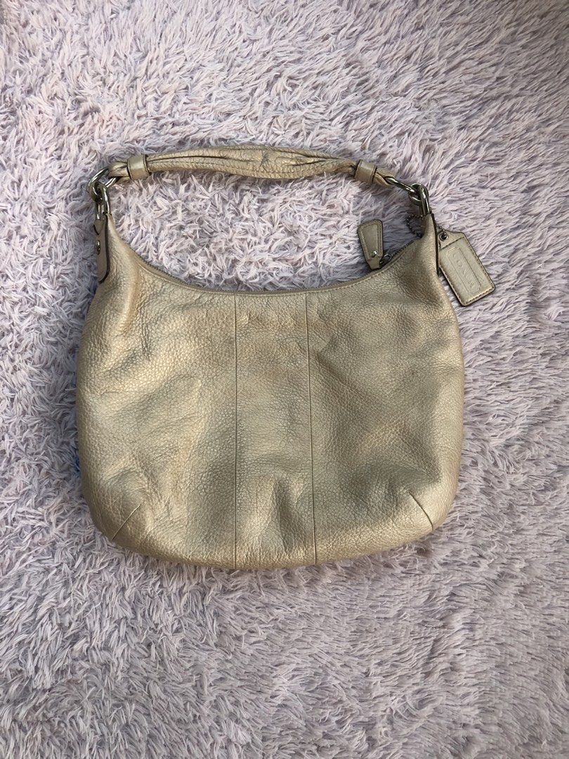 Coach Metallic Gold Leather Shoulder Bag (Category: Luxury Bags & Wallets) located in Montevista. Submitted by rdthriftshub (Listing ID 1470155677, Image 2). Description: - Brand: Coach - Style: Classic hobo shoulder bag - Material: Textured metallic gold leather - Closure: Zip-top opening with front flap and metal turnlock pocket - Details: Includes matching hangtag and interior creed patch with serial number - Interior: Light pink fabric lining