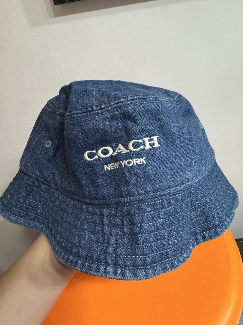 Coach New York Denim Bucket Hat (Category: Babies & Kids Fashion) located in Valenzuela. Submitted by sofiasticated.decluttering (Listing ID 1470171133, Image 1). Description: - Brand: Coach - Style: Denim bucket hat with embroidered white logo - Wash: Classic blue wash denim - Interior: Brown signature C monogram lining with black Coach branding tape - Size: S/S - Condition: Great casual accessory for sunny days out - Shipping or meet-up options