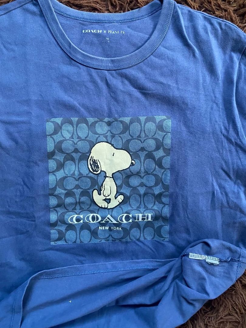 Coach x Peanuts Snoopy Blue T-Shirt (Category: Activewear) located in Manila. Submitted by ayvanz (Listing ID 1470279758, Image 2). Description: - Brand: Coach x Peanuts - Item: Blue t-shirt with Snoopy graphic print - Details: Signature Coach monogram pattern inside the graphic box, classic crew neck, short sleeves - Fit: Relaxed fit - Perfect for: Casual everyday wear and collector enthusiasts.