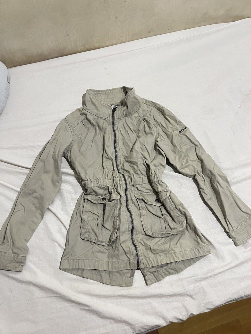 Columbia Beige Utility Jacket with Drawstring Waist (Category: Coats, Jackets and Outerwear) located in San Fernando. Submitted by angelhave_wings (Listing ID 1470290956, Image 2). Description: - Brand: Columbia - Color: Beige - Material: Durable cotton canvas - Design: High collar, full zip front, and button cuffs - Pockets: Double front utility pockets with flap closures - Silhouette: Fitted elasticized waist for a structured look - Condition: 
