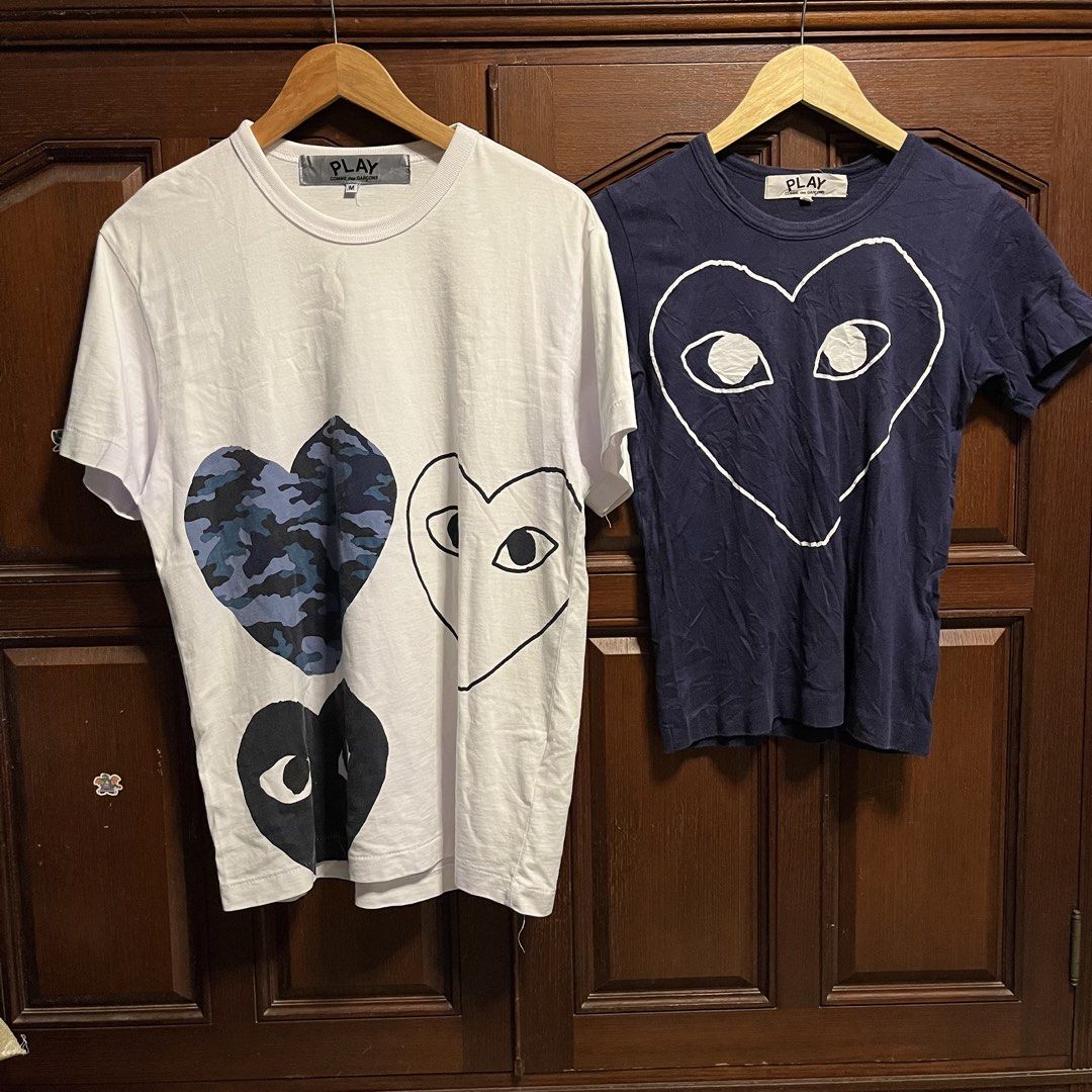 COMME des GARÇONS PLAY T-Shirts (Category: Shirts) located in Manila. Submitted by thriftyyyyy. (Listing ID 1470290220, Image 1). Description: - Authentic COMME des GARÇONS PLAY t-shirts (Made in Japan, 100% cotton, hand wash only) - Item 1: White short-sleeve tee with multi-heart & camo graphics, Size M (AD2019) - Item 2: Dark blue tee with large outline heart graphic, Size XS (AD2012) - Features classic PLAY branding on collar tags - DM for inq