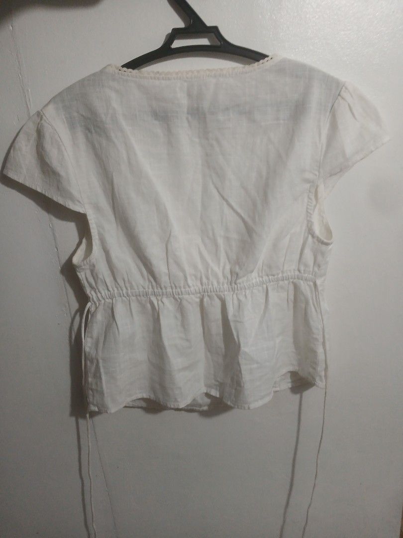 Cotton On White Short Sleeve Top (Category: Activewear) located in Los Banos. Submitted by kiezsah (Listing ID 1470256794, Image 2). Description: - Brand/Model: Cotton On - Size: Small but Fits Medium-Large - Color: White - Design: Deep v-neck with front tie detail, short flutter sleeves, and cinched back waist - Material: Lightweight fabric - Condition: Brand new without tag / Excellent - Styling: Perfect to pair with jeans or skirts.