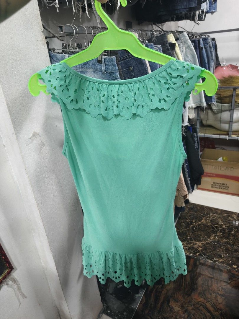 Coulandi Green Sleeveless Ruffle Top (Category: Sleeveless) located in Binan City. Submitted by makinpeso0622 (Listing ID 1470183438, Image 2). Description: - Brand: Coulandi - Style: Green sleeveless top with V-neckline and hem ruffles - Details: Cut-out floral patterns and visible inner lace layer at the chest - Fabric: Soft, lightweight, and cool to wear - Condition: Good, clean, and ready to wear - Perfect for: Casual days out with jeans or s
