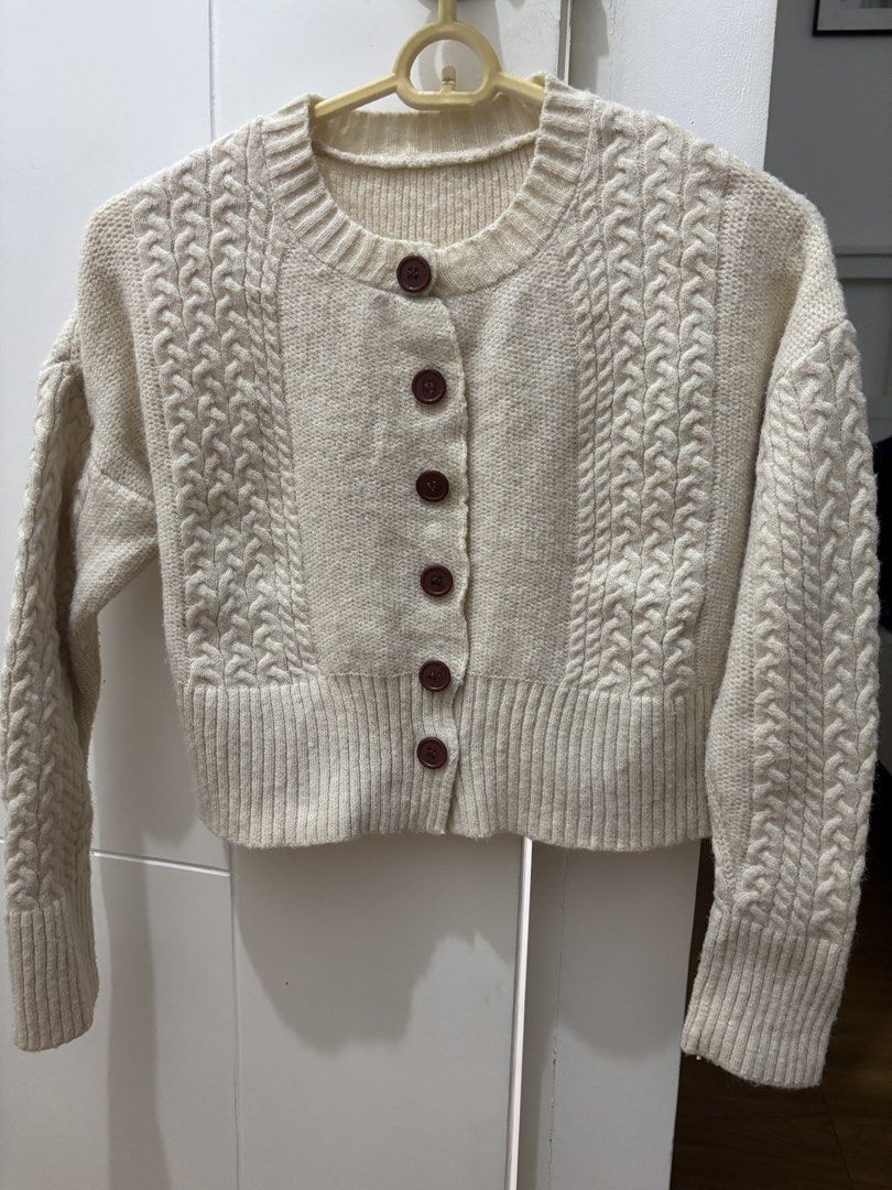 Cream Cable Knit Button-Up Cardigan (Category: Coats, Jackets and Outerwear) located in Bacoor. Submitted by tummybeautyph (Listing ID 1470246598, Image 1). Description: - Color: Cream with contrasting dark brown buttons - Material: Thick, cozy, and warm knit - Design: Chunky cable knit pattern on front and back - Fit: Cropped length with ribbed hem, cuffs, and round neckline - Condition: Brand new / Excellent.