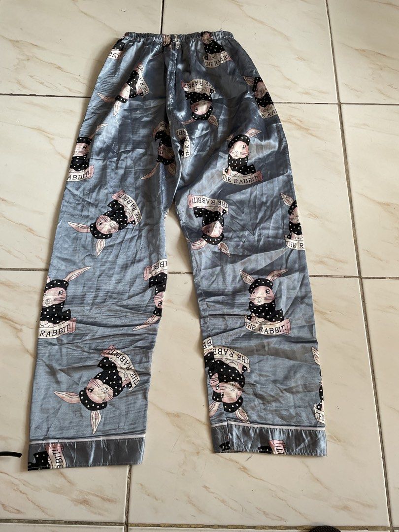 Cute Rabbit Print Satin Pajama Set (Category: Undergarments & Loungewear) located in Pasig City. Submitted by khaleisi (Listing ID 1470227972, Image 3). Description: - Color: Stylish greyish-blue with all-over 'THE RABBIT!' cartoon graphic print - Set includes: Short-sleeve button-up top and matching long pants - Features: Convenient left chest pocket and chic black polka dot headscarf bunny design - Material: Soft, silky, and lightweight satin f
