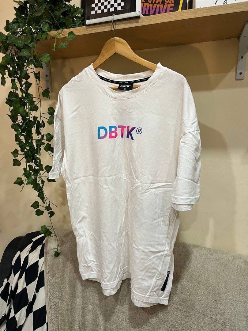 DBTK White Graphic T-Shirt (Category: Tshirts & Polo Shirts ) located in Manila. Submitted by tenshiii185 (Listing ID 1470233813, Image 1). Description: - Brand: DBTK - Color: White with colorful gradient branding - Fit: Oversized streetwear style - Material: Standard cotton - Details: Crew neck with repeated DBTK inner taping and small black tag on the lower left hem - Size XL.