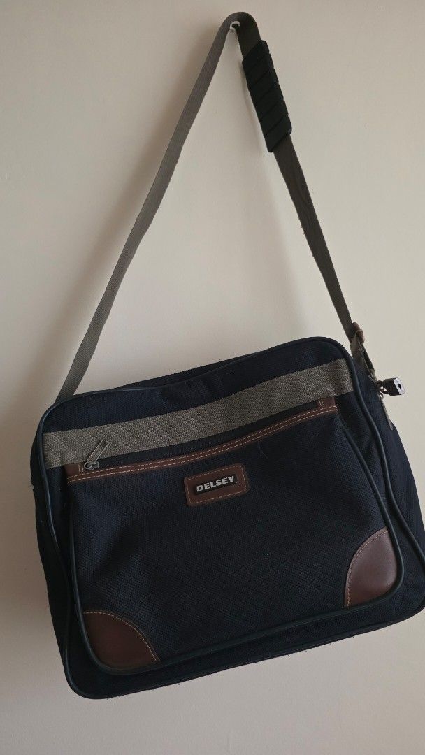 Delsey Canvas Messenger Bag with Shoulder Strap (Category: Sling Bags) located in Las Pinas. Submitted by lovedbymariee (Listing ID 1470187160, Image 1). Description: - Brand: Delsey - Color: Dark navy blue canvas with brown leather trim - Design: Front zippered pocket with olive green stripe and included padlock - Comfort: Adjustable canvas shoulder strap with padded grip handle.