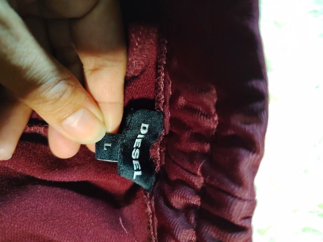 Diesel Maroon Track Pants Size L (Category: Joggers) located in Caba. Submitted by valerie_18947 (Listing ID 1470271787, Image 3). Description: - Brand/Model: Diesel Maroon Track Pants - Size: Large - Design: Black side stripes and front leg stitching details - Pockets: Two front zipper pockets with metallic hardware - Waistband: Adjustable drawstring with dark cords - Material: Comfortable cotton blend - Style: Perfect for casual streetwear and 
