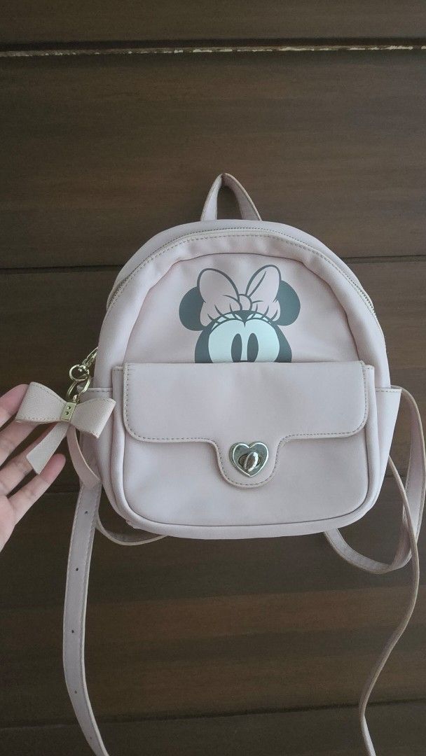 Disney Minnie Mouse Pink Mini Backpack with Bow (Category: Babies & Kids Fashion) located in Quezon City. Submitted by nini25ic (Listing ID 1470153792, Image 1). Description: - Color: Light pink with adorable Minnie Mouse print - Pocket: Front flap pocket with a cute heart-shaped turn-lock closure - Detail: Sweet little bow attached near the base - Interior: Pink satin lining with a secure zip compartment and slip pockets - Straps: Comfortable, a
