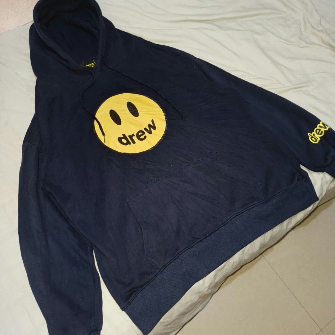 Drew House Mascot Hoodie Navy Blue (Category: Coats, Jackets and Outerwear) located in Manila. Submitted by collinvien123 (Listing ID 1470281237, Image 2). Description: - Brand: Drew House - Color: Dark Navy Blue with Yellow Graphics - Size: Large - Design: Large smiley face with 'drew' on chest, yellow lettering on left sleeve - Material: Comfortable fleece cotton - Features: Adjustable drawstrings with metal tips, front kangaroo pocket, ribbed 