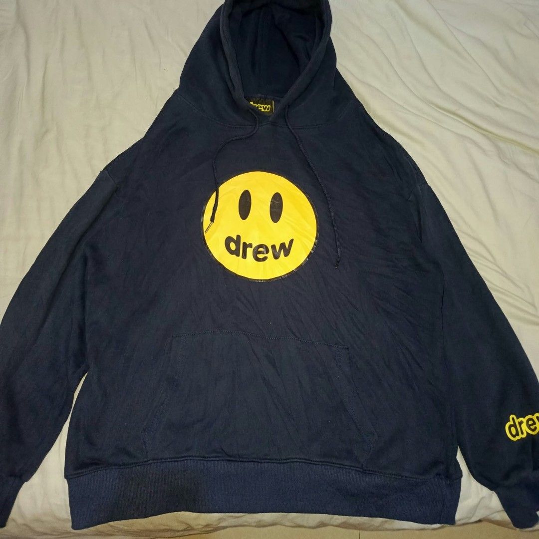 Drew House Mascot Hoodie Navy Blue (Category: Coats, Jackets and Outerwear) located in Manila. Submitted by collinvien123 (Listing ID 1470281237, Image 1). Description: - Brand: Drew House - Color: Dark Navy Blue with Yellow Graphics - Size: Large - Design: Large smiley face with 'drew' on chest, yellow lettering on left sleeve - Material: Comfortable fleece cotton - Features: Adjustable drawstrings with metal tips, front kangaroo pocket, ribbed 