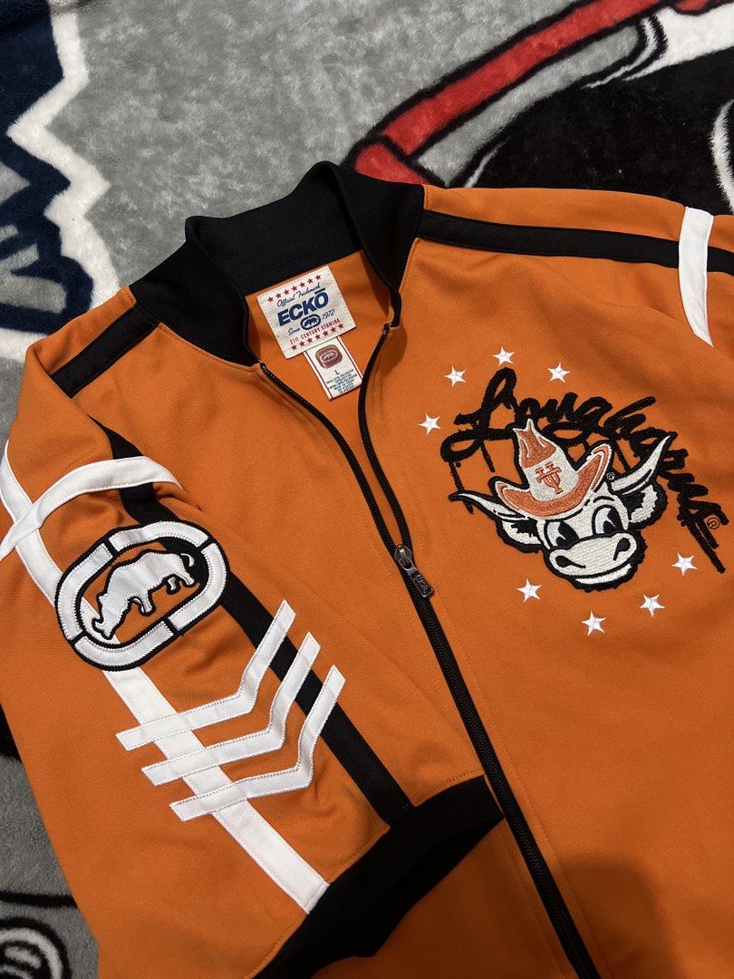 Ecko Unltd. Short Sleeve Track Jacket Orange (Category: Coats, Jackets and Outerwear) located in Tanza. Submitted by 1954_street (Listing ID 1470305986, Image 2). Description: ECKO large 27x31 excellent condition 1500 - Brand: Ecko Unltd. (Official Tagged Product) - Size: Large - Color: Vibrant orange with black/white contrast piping - Design: Large embroidered cowboy bull logo on chest, graphics on upper and lower back - Features: Full zip closu