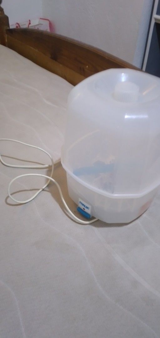 Farlin electric bottle sterilizer and dryer (Category: Breastfeeding & Bottle Feeding) located in Quezon City. Submitted by roxasjr86 (Listing ID 1470195711, Image 2). Description: - Brand: Farlin - Type: Electric bottle sterilizer - Color: Translucent white with blue tongs included - Features: Removable cover, internal bottle rack, and multiple prongs to hold bottles upright - Controls: Easy-access power switch button on the front with attached 